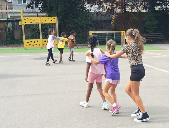 Children playing together in a group on a paved playground during the day.