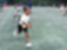 Young boy running with a smile during sports day activity, children playing nearby.
