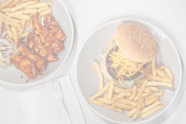 Plates of chicken wings and a cheeseburger with fries