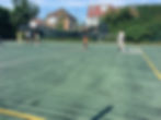 Children playing sports on a green court, football goal, basketball hoop background.