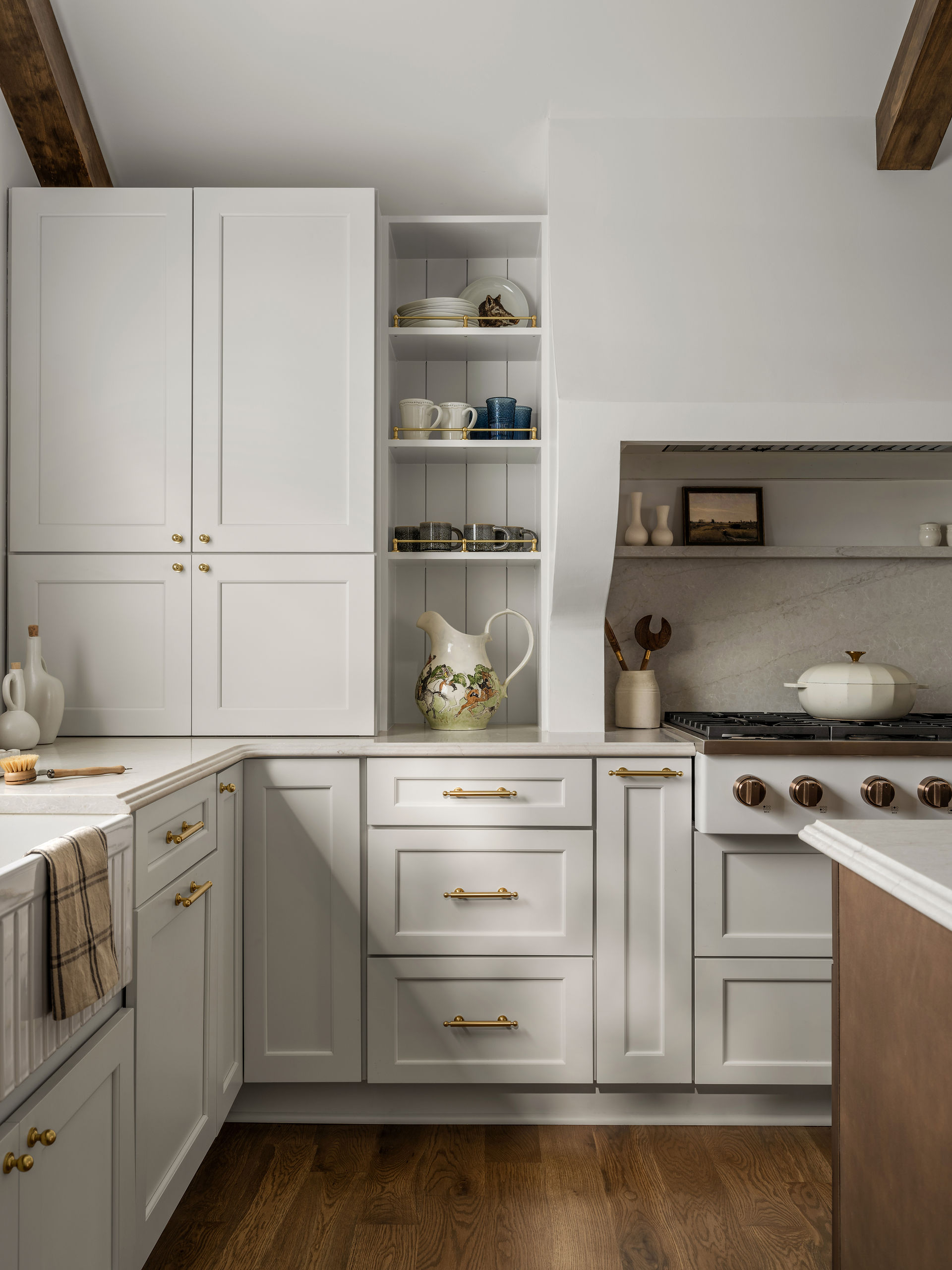 Organic modern kitchen renovation with custom white cabinetry, brass hardware, and open shelving. 