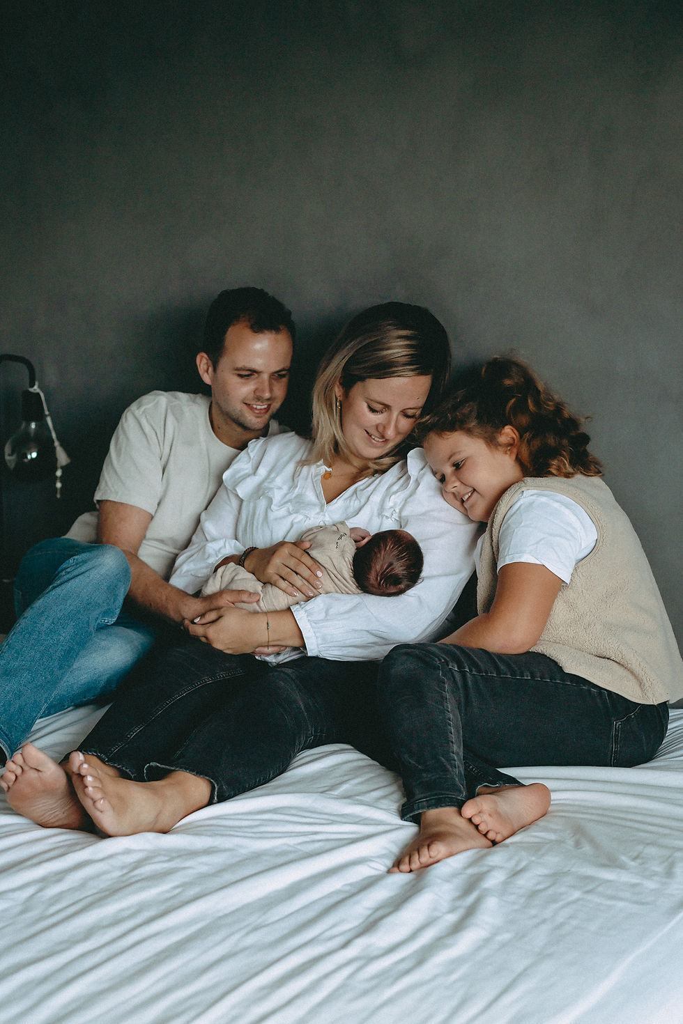 Lifestyle newborn fotografie van gezin met pasgeboren baby thuis in Dordrecht en Rotterdam op bed in zacht natuurlijk licht