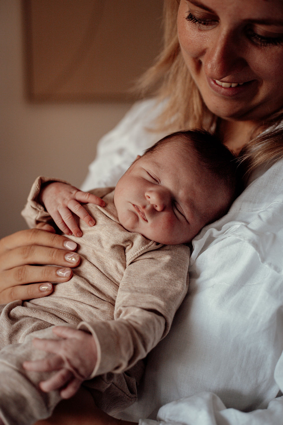 Lifestyle newborn shoot thuis in Dordrecht en Rotterdam met moeder die haar pasgeboren baby liefdevol vasthoudt in natuurlijk licht