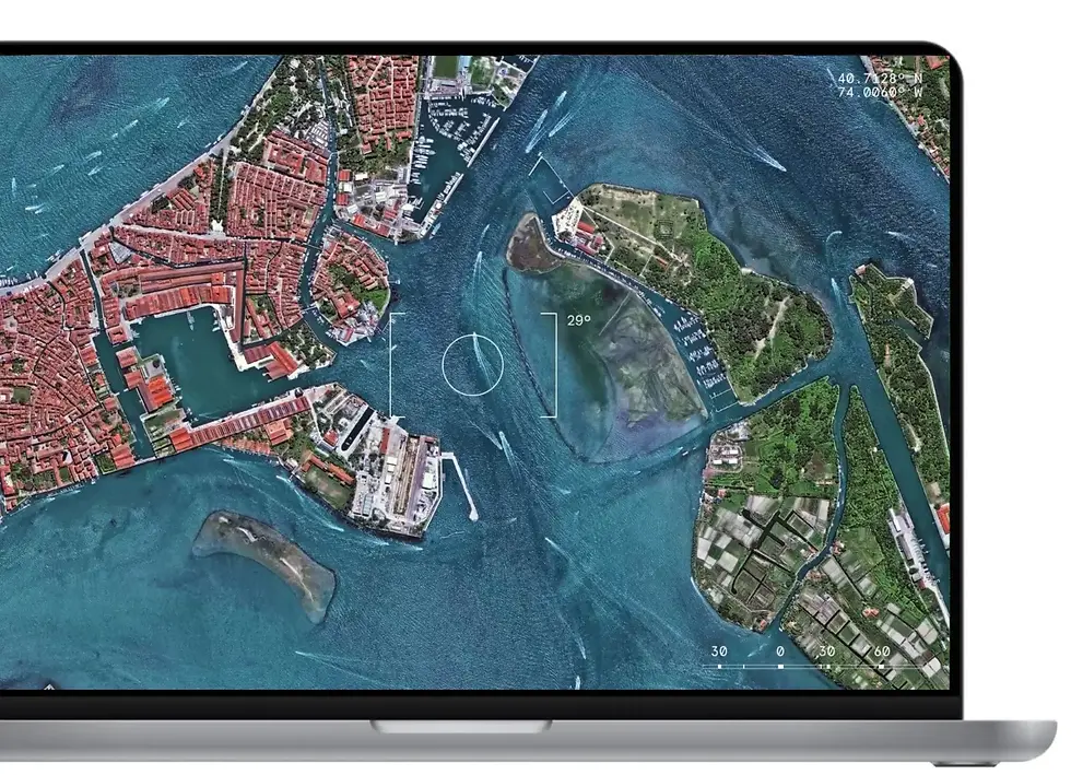 Laptop screen displaying a detailed satellite image of a coastal city with waterways and islands, emphasizing geospatial technology