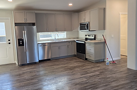 Empty residential kitchen with grey cabinets, appliances and wood flooring