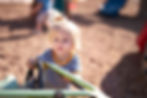 Young child in striped shirt playing with a toy car at a playground.