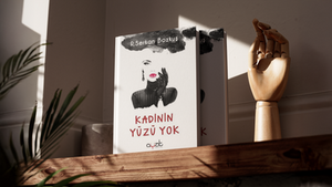 Kimlik, gizem ve kadın temalarını soyut ve sanatsal bir illüstrasyon diliyle ele alan iddialı bir editoryal kurgudur. Beyaz negatif alanın ustaca kullanıldığı kapak düzeninde, siyah mürekkep/sulu boya lekesi estetiğiyle çizilen eldivenli kadın figürü ve sadece kırmızı dudaklar ile göz hattının ön plana çıkarılması, anlatılmak istenen derin felsefi temayı sarsıcı bir biçimde somutlaştırmaktadır. Üst kısımdaki koyu leke içerisine yerleştirilen yazar ismi kompozisyona dengeli bir giriş sağlarken, alt bölümde konumlandırılan el yazısı karakterindeki dinamik kırmızı başlık tipografisi illüstrasyonun sanatsal ruhunu doğrudan desteklemektedir. En alt bölüme yerleştirilen "Ayzıt Yayınları" kurumsal amblemiyle bütünselliği ve yayıncılık standartları sağlanan bu rafine mizanpaj, editoryal titizliği ve güçlü tasarım zıtlıklarını bir potada eriterek portfolyonuz için akılda kalıcı, lirik ve profesyonel bir kitap tasarımı örneği sunmaktadır.