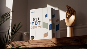 Eğitim yayıncılığı standartlarını modern, dinamik ve kurumsal bir çizgiyle ele alan iddialı bir editoryal mizanpaj çalışmasıdır. Açık renkli ve ferah arka plan üzerinde yükselen asimetrik yerleşimli mavi, vizon ve gri geometrik eşkenar dörtgenler ile yukarıdan sarkan dikey ince çizgiler, öğrencilere sınav sürecinin gerektirdiği odaklanmayı, analitik düşünceyi ve sistemli yapıyı görsel olarak hissettirmektedir. Kitabın dizgi-mizanpaj omurgasını besleyen tasarımda; sol taraftaki kalın sans-serif "5'Lİ YDT" tipografisi ile soft tonlardaki "DENEME" başlığı arasında güçlü bir görsel hiyerarşi kurulmuş, alt ve üst bölümlere yerleştirilen dikey klavuz çizgileriyle de kompozisyon dengelenmiştir. Sol alt köşede konumlandırılan siyah dairesel "Berk Hoca" kurumsal amblemi ise, editoryal bütünlüğü tamamlayarak yayına hem kurumsal bir ciddiyet hem de hedef kitlesi olan genç sınıflara hitap eden prestijli ve yenilikçi bir karakter kazandırmaktadır.