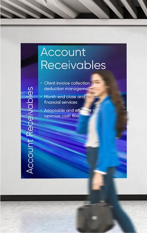 A woman in a blue jacket walking past a large poster on the wall with information about account receivables
