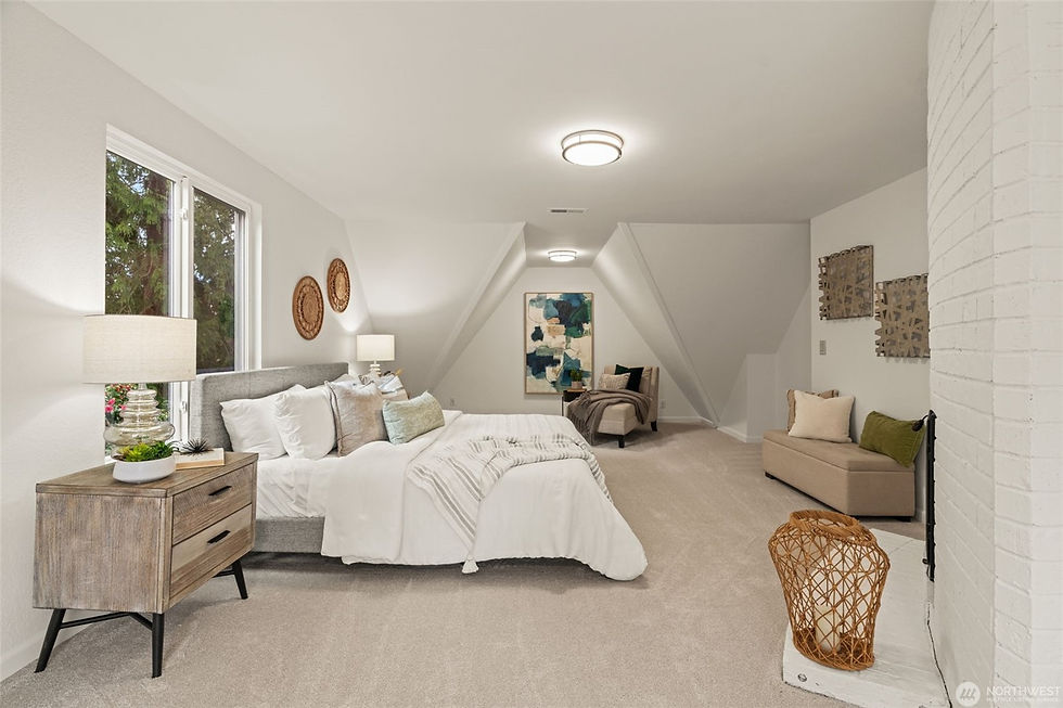 Spacious bedroom with a large bed, white bedding, and wooden nightstand. Warm lighting, abstract art, and cozy seating create a calm mood.