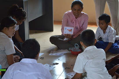 Cambodian teacher sitting on the floor with children.jpg