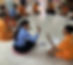 Teacher sits in a circle with students with disabilities on the floor and gives one a high