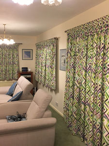 Armchairs in front of patterned curtains