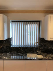 A kitchen window with vertical blinds