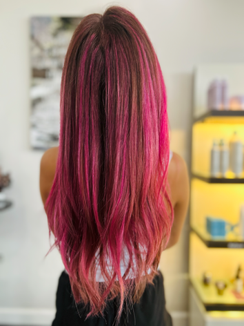Back view of a client with long, straight hair vividly colored in a bright, glossy magenta pink shade.