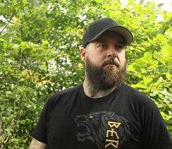 Kunde im Berserker-Shirt steht im Wald und blickt stolz in die Kamera