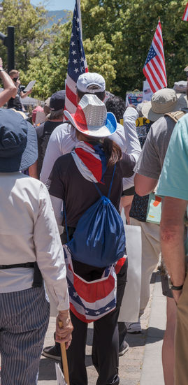 A woman who is absolutely covered in red, white, and blue clothing, from the cowboy hat to the bunting around her waist.