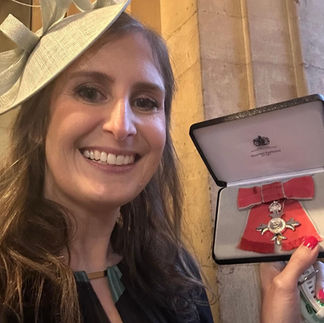Smiling lady in hat holding OBE