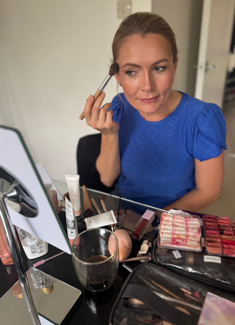 a lady applies makeup in a mirror during a makeup lesson