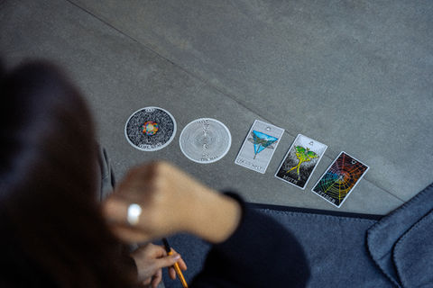 Von oben fotografierte Teilnehmerin in einem Innenraum, die verschiedene mystische Karten vor sich betrachtet – Teil einer Kailo Nature Therapy Sitzung.