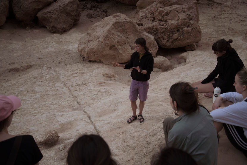 Menschen, die in der Wüste auf dem Boden sitzen und einer sprechenden Person zuhören bei einem Systemischen Naturtherapie-Retreat in der Wüste in Ägypten, El Gouna 