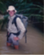Stephen O'Keefe in his twenties wearing jungle clothing, and knee deep in a jungle stream