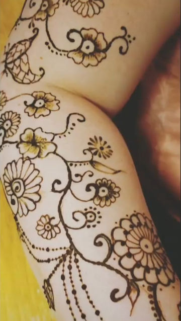 This photo shows arm henna from wrist to a bit above the elbow. the henna is traditional Indian style henna including flowers, swirls, chandelier elements, and jhumka elements.