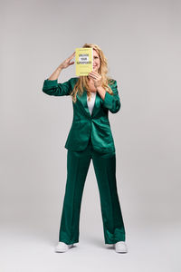 Woman in green suit playfully hides behind a book