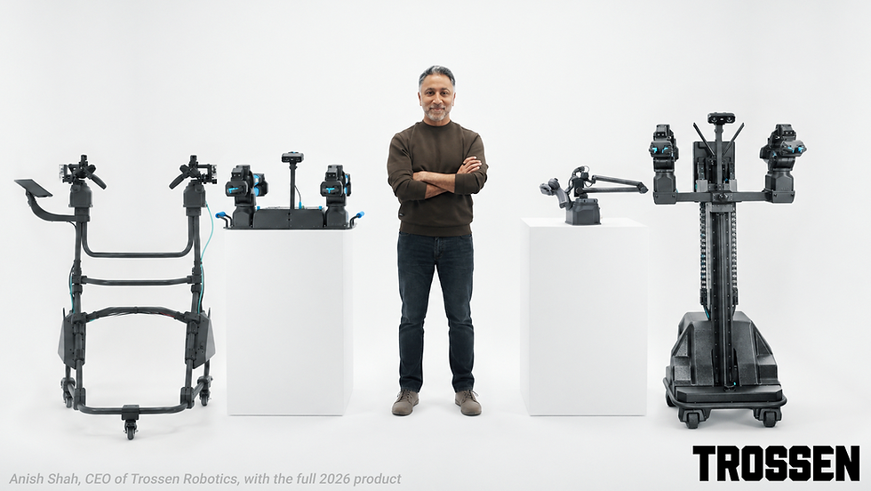 Anish Shah stands smiling with crossed arms beside black Trossen Robotics prototypes on white pedestals; TROSSEN text below.