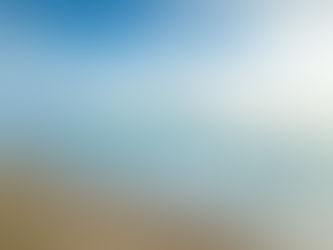 Calm beach scene with gentle waves on sandy shore under a partly cloudy sky. The ocean is a clear blue, creating a serene atmosphere.