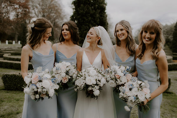Bride with her bridesmaids holding matching floral bouquets, smiling in natural light - elegant and joyful wedding morni