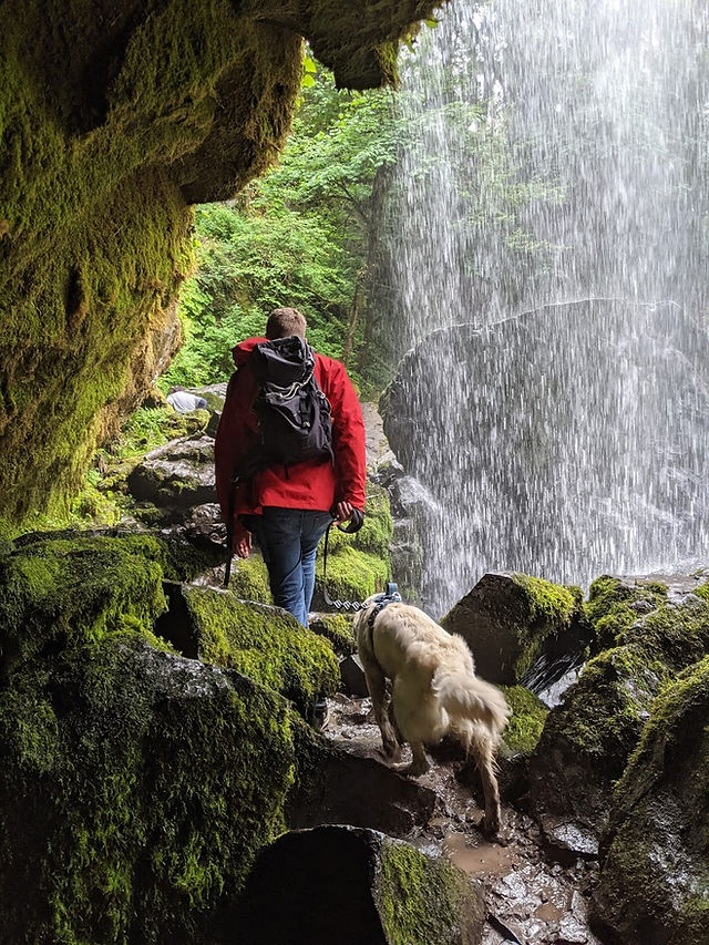Hiker walking under waterfall at Middle Falls on Little Mashal Falls Trail