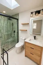 ADU bathroom with green tile shower, wood vanity, skylight and matte black fixtures in Medford, Oregon