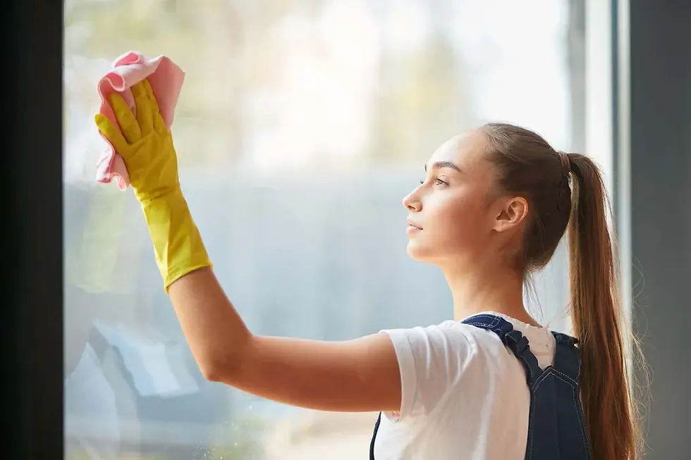 A person wiping a window glass to demonstrate how to clean a house professionally