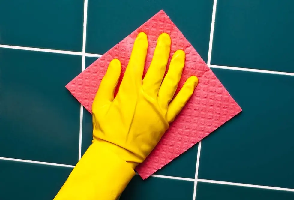 A person scrubbing bathroom tile grout during an apartment deep cleaning