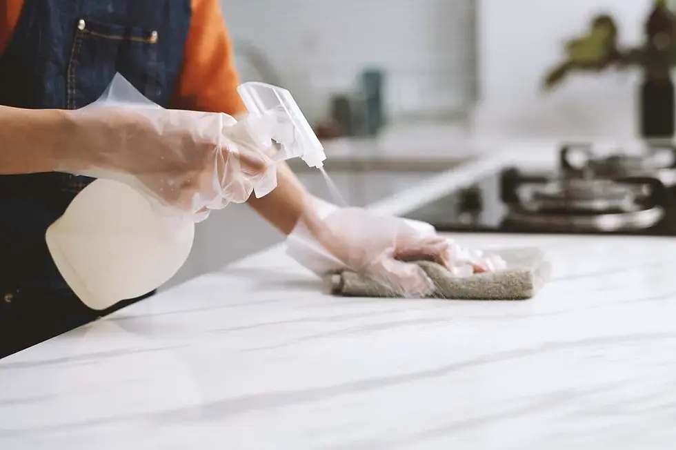 A person wearing cleaning gloves, sanitizing a kitchen counter in a new apartment.