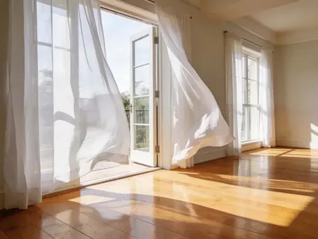 Bright and tidy living room with open windows catching a fresh summer breeze.