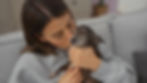 Young hispanic woman affectionately kissing her senior chihuahua in a cozy living room..jp