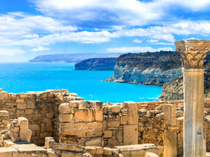 Ancient Greek ruins with a preserved marble column overlooking the turquoise Mediterranean Sea and dramatic coastal cliffs in Greece.