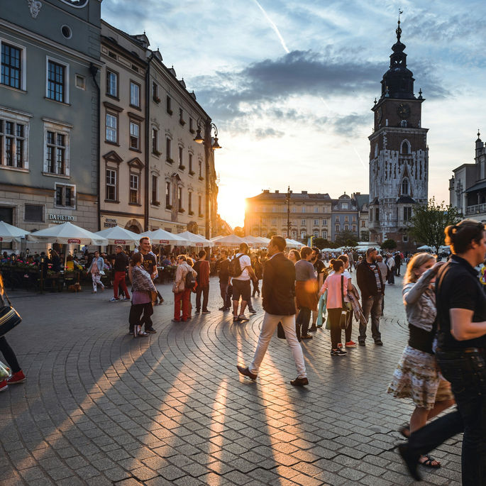 People walking around city at sunset.