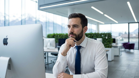 close up de um homem numa camisa branca e gravata sentado numa secretária com olhar pensativo. The background is softly blurred,The lighting is bright and clean, with cool tones that emphasize a professional atmosphere. The composition highlights precision, curiosity, with sharp focus on man's face.