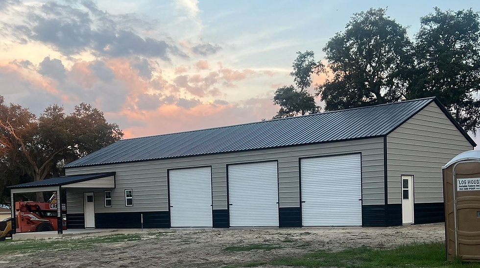 Custom metal garage with three white bay doors at sunset.