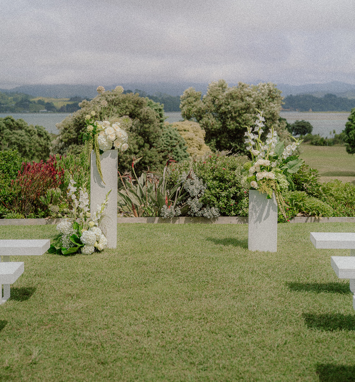 Outdoor wedding ceremony with white and green floral arrangements on plinths