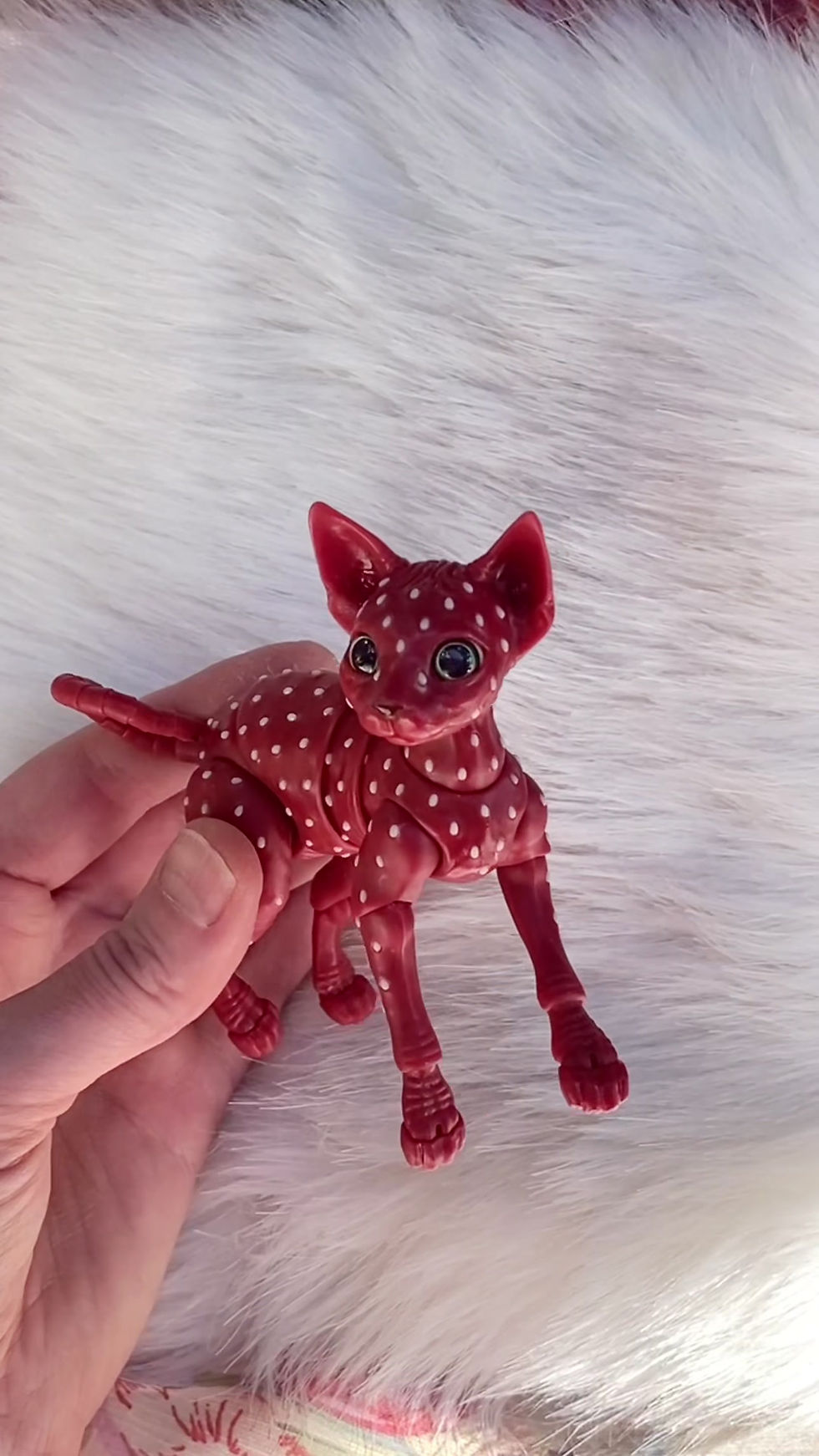 Thumbnail: Hand holding a miniature red strawberry BJD cat to show scale and flexibility.