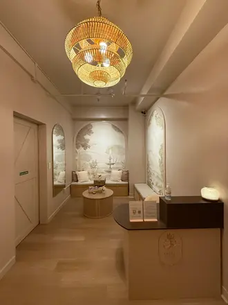 Thara Thai Spa reception counter with a woven bamboo chandelier and landscape mural background.