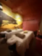 Safari-themed spa room with an African sunset and giraffe wall mural behind two massage beds.