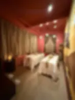 Warmly lit couple's spa room with safari decor, lantern lights, and privacy curtains.