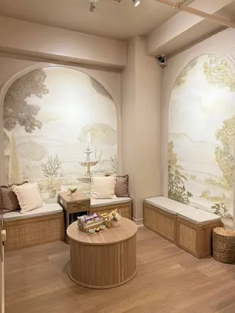 Spa waiting area featuring arched landscape murals and wooden storage benches with cushions.