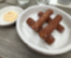 Churros laid out in a hashtag symbol. On the side is a small bowl of lemon curd dip.
