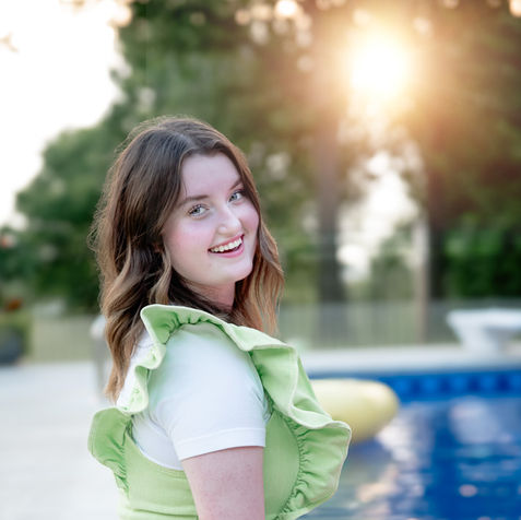 senior girl smiles at the pool during her golden hour photo session